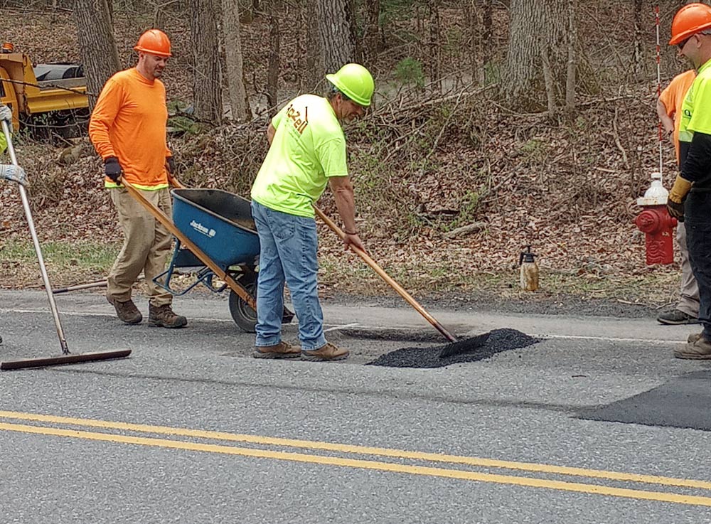 Workers raking blacktop patch
