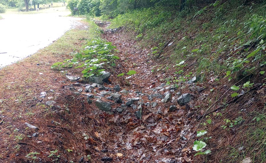 A series of stacked stone check dams in a ditch.